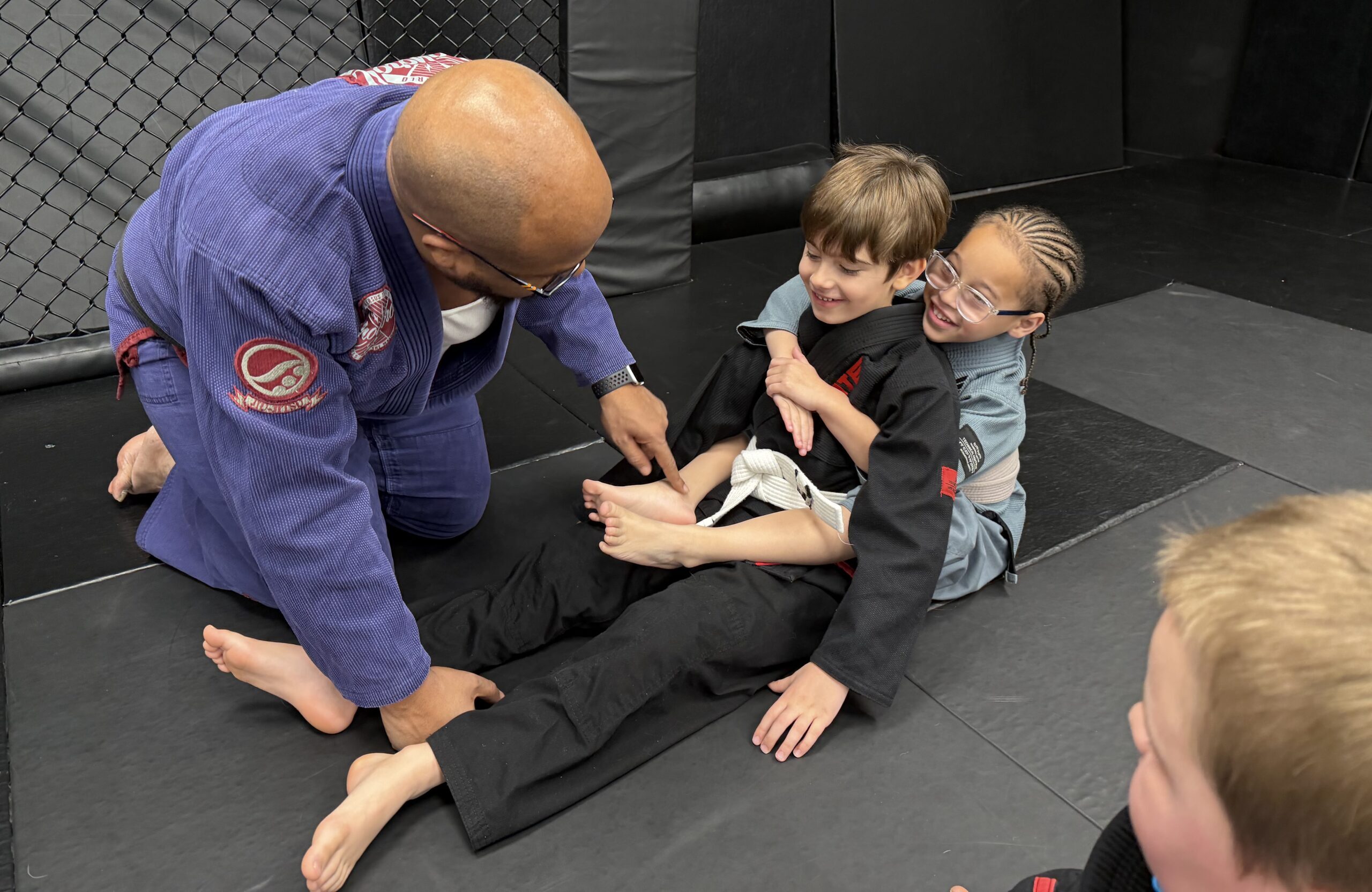 Kids BJJ Fundamentals Coaching in Harrisburg Kids practicing Brazilian Jiu-Jitsu while a coach provides hands-on instruction at Deep Water BJJ in Harrisburg.
