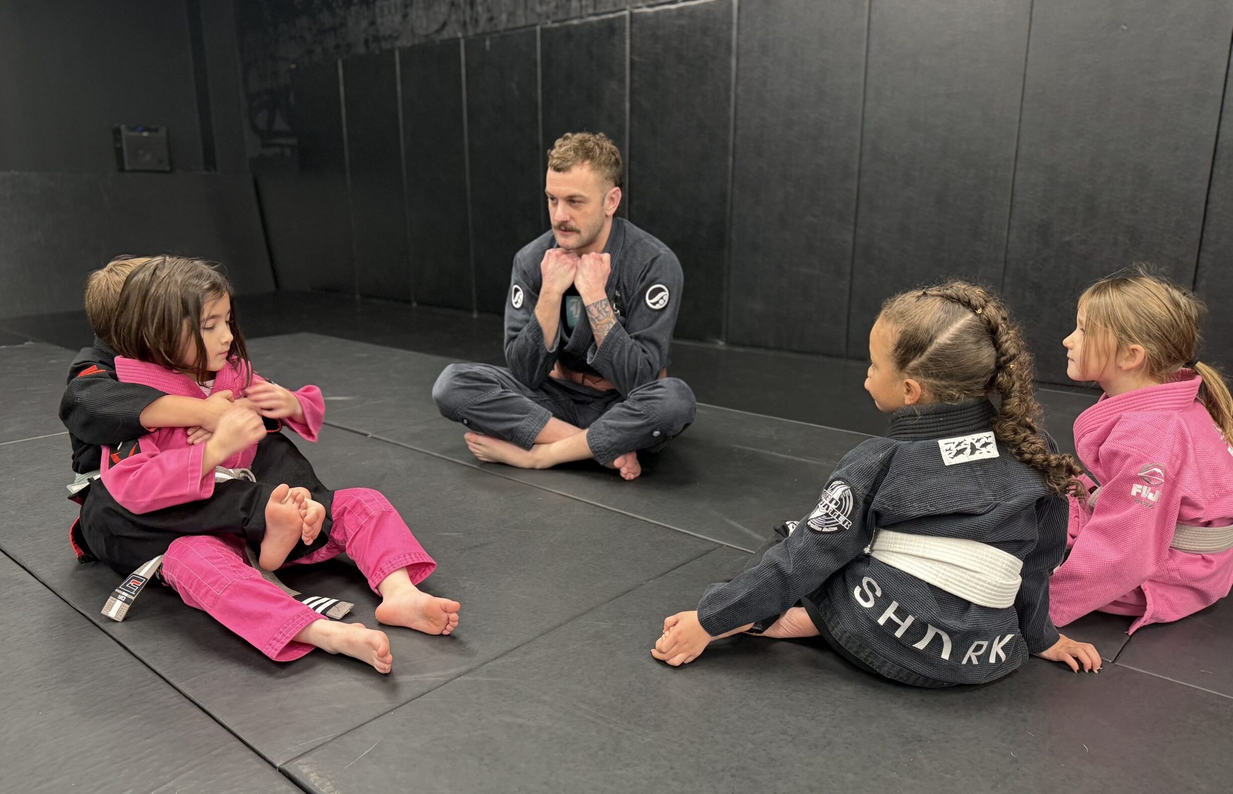 Kids BJJ Coaching and Technique Practice in Harrisburg Kids practicing a Brazilian Jiu-Jitsu technique while a coach instructs them at Deep Water BJJ in Harrisburg.