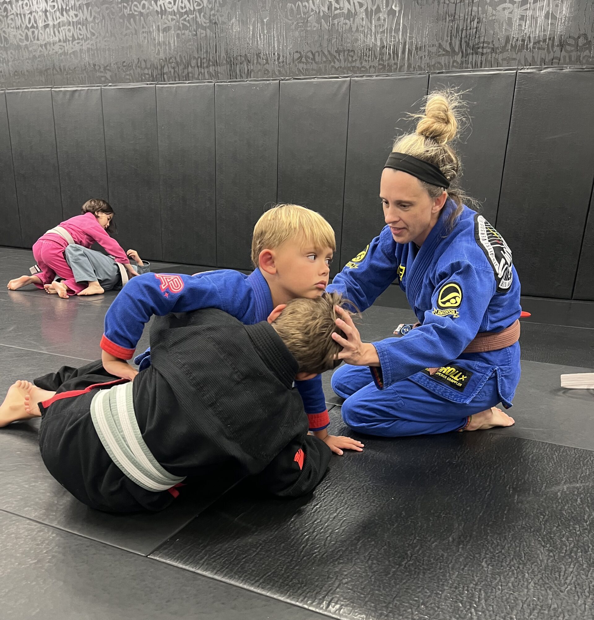 Kids Brazilian Jiu-Jitsu Coaching at Deep Water BJJ Coach guiding two children through a Brazilian Jiu-Jitsu position at Deep Water BJJ in Harrisburg