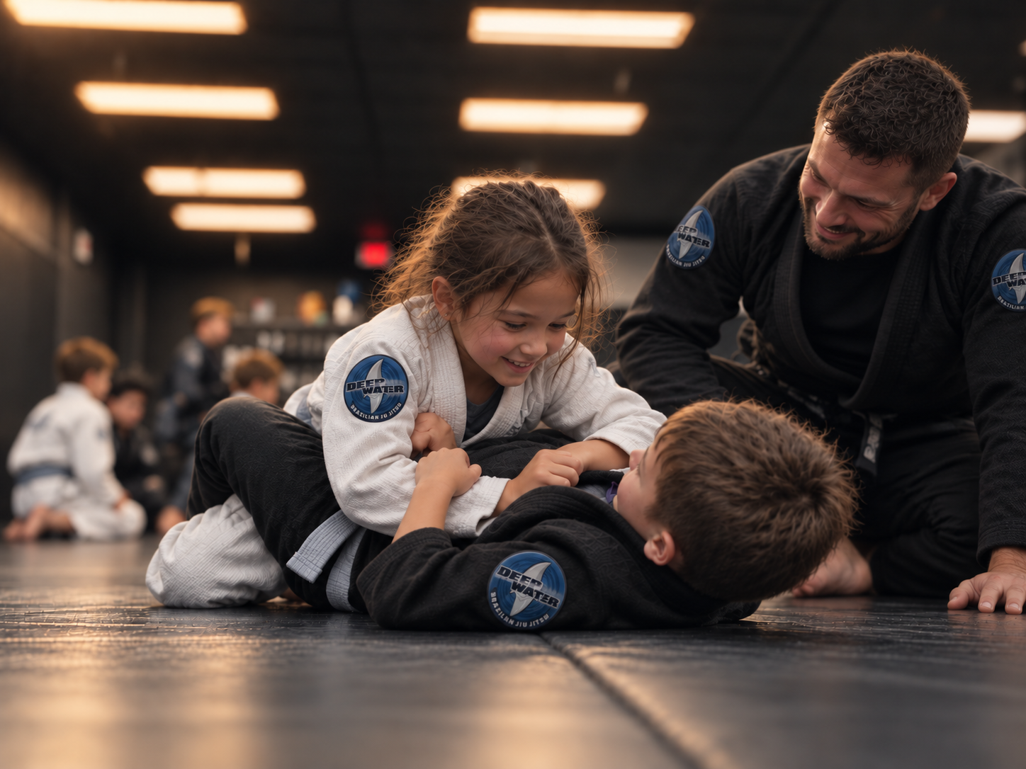 Two children practicing Brazilian Jiu-Jitsu while a coach watches during a structured kids martial arts class