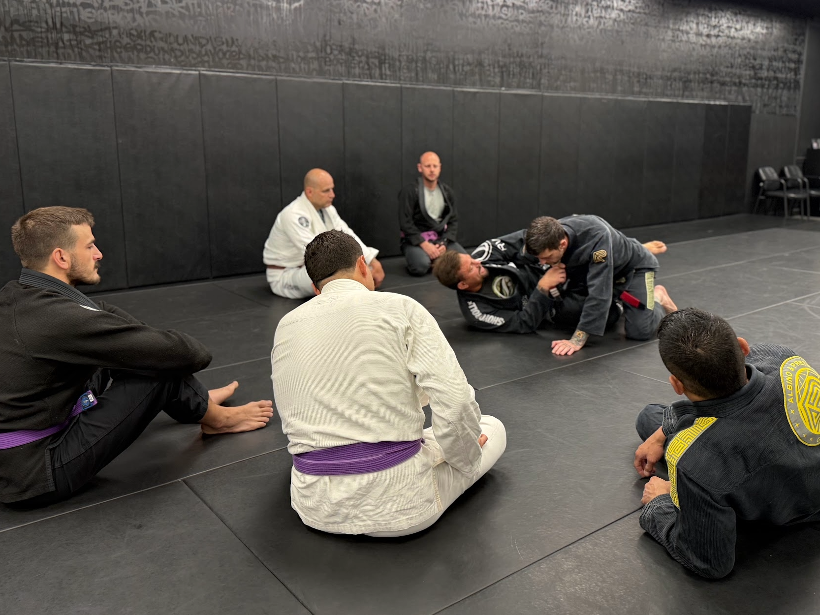Students watching a Brazilian Jiu-Jitsu technique demonstration during class at Deep Water BJJ.
